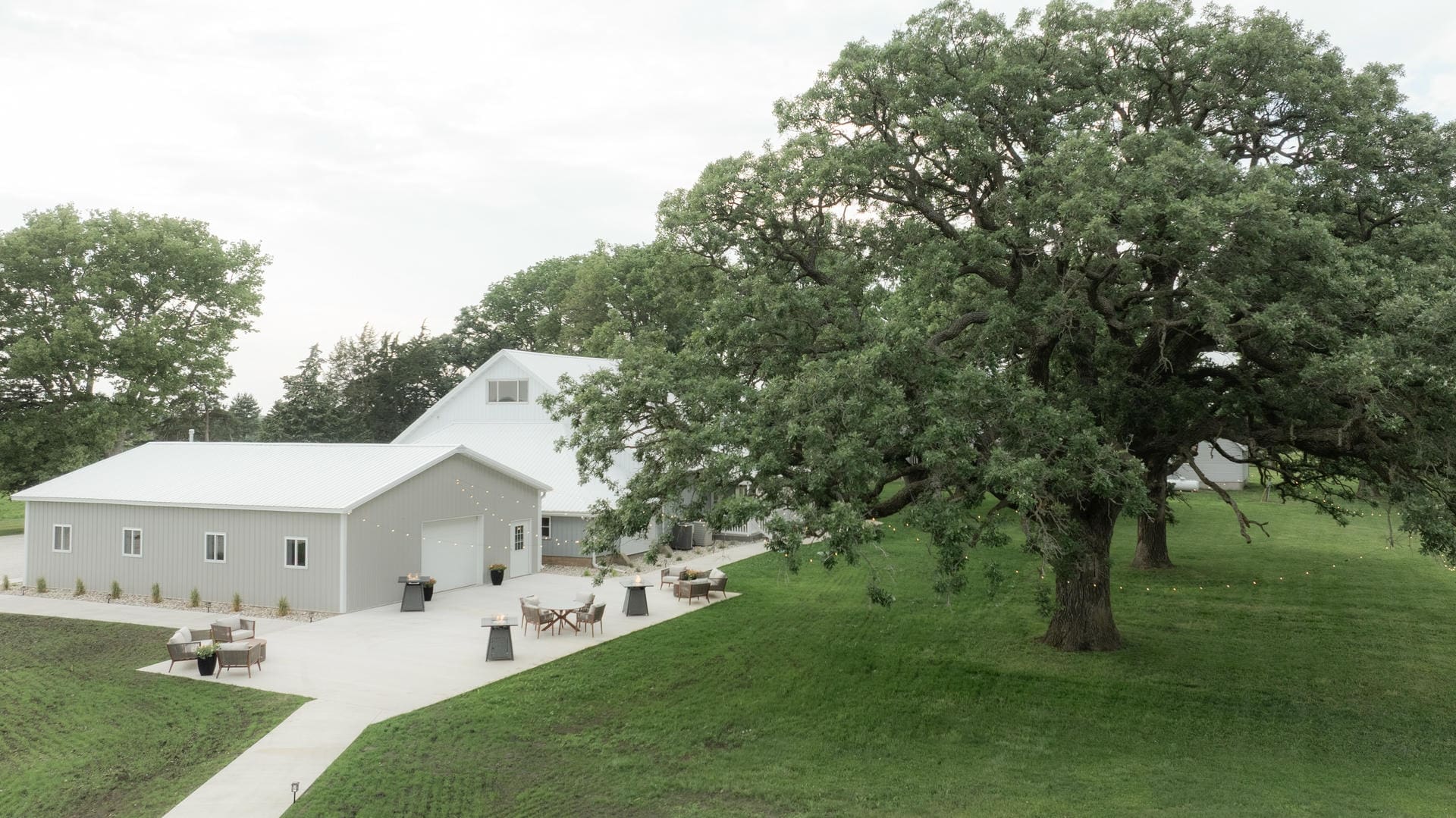Aerial view of The Era's all-in-one wedding venue property in Iowa — barn, patio, and grounds under the oak trees