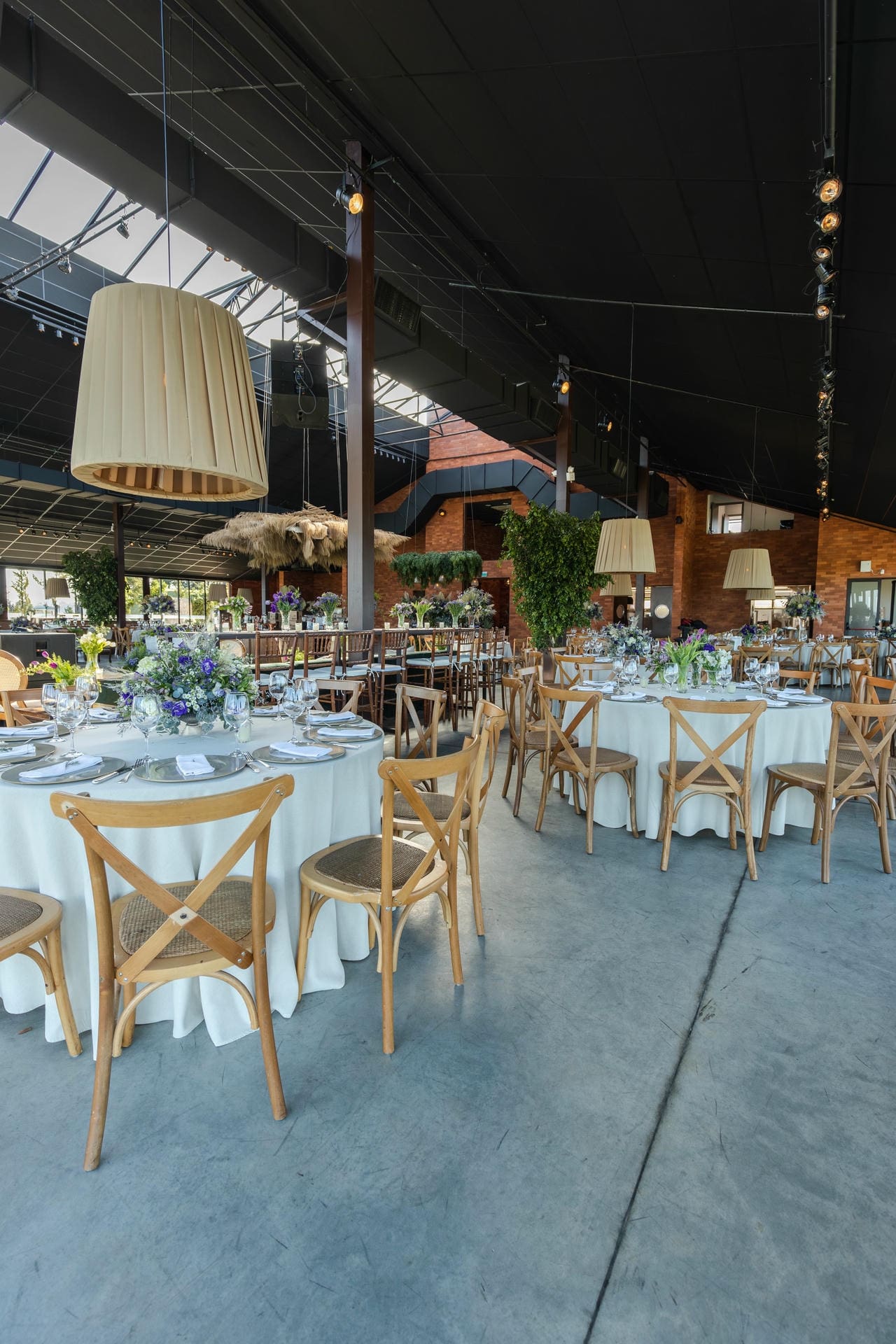 Wedding reception tables set with florals and wooden chairs inside a spacious Iowa wedding venue