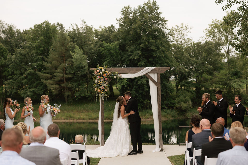 Bride and groom's first kiss during an outdoor wedding ceremony at The Era in Iowa
