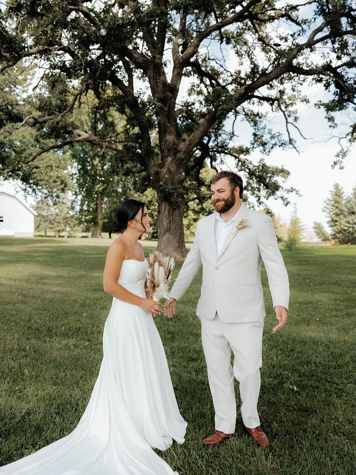 Bride and groom smiling together under an oak tree at an Iowa wedding venue